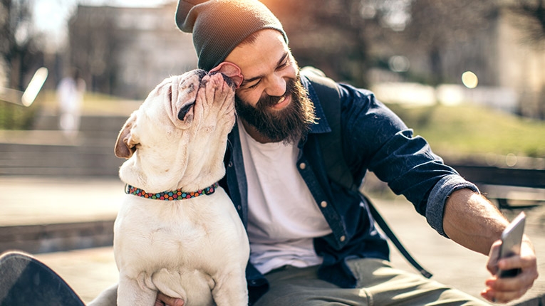 Young millennial guy with his bulldog taking a selfie